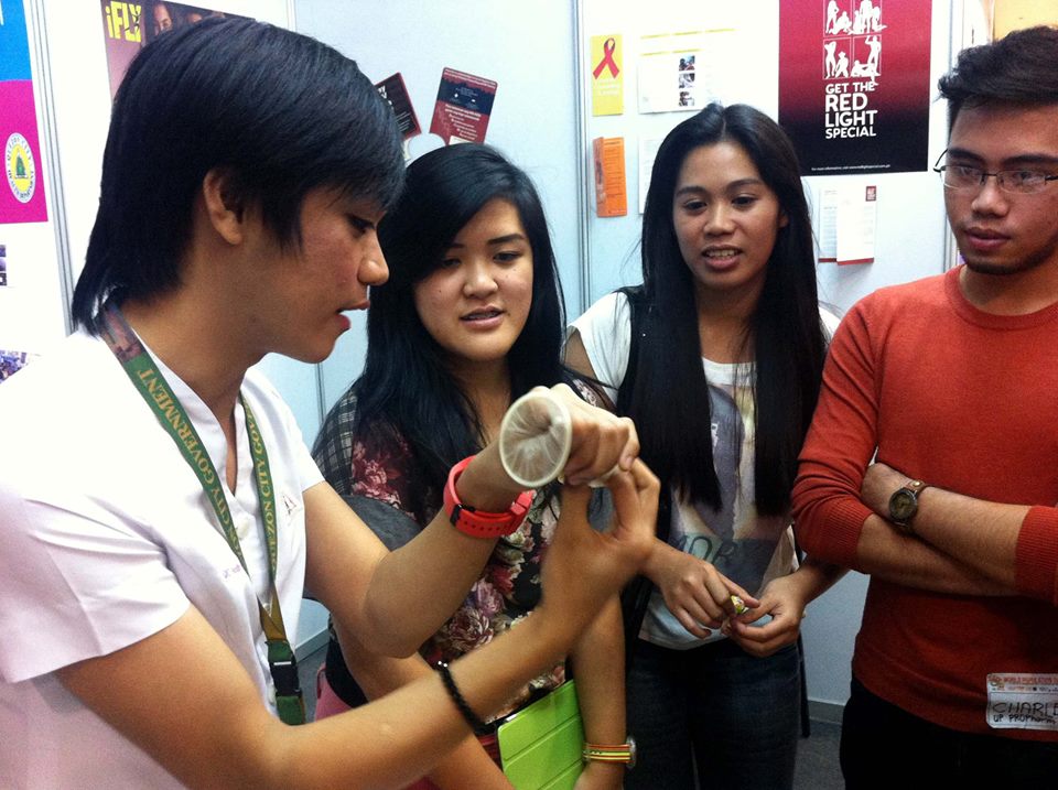 Devine David, HIV Peer Counselor from Klinika Bernardo, shows participants of World Population Day how to properly use a female condom. Photo by Luis Adrian Hidalgo